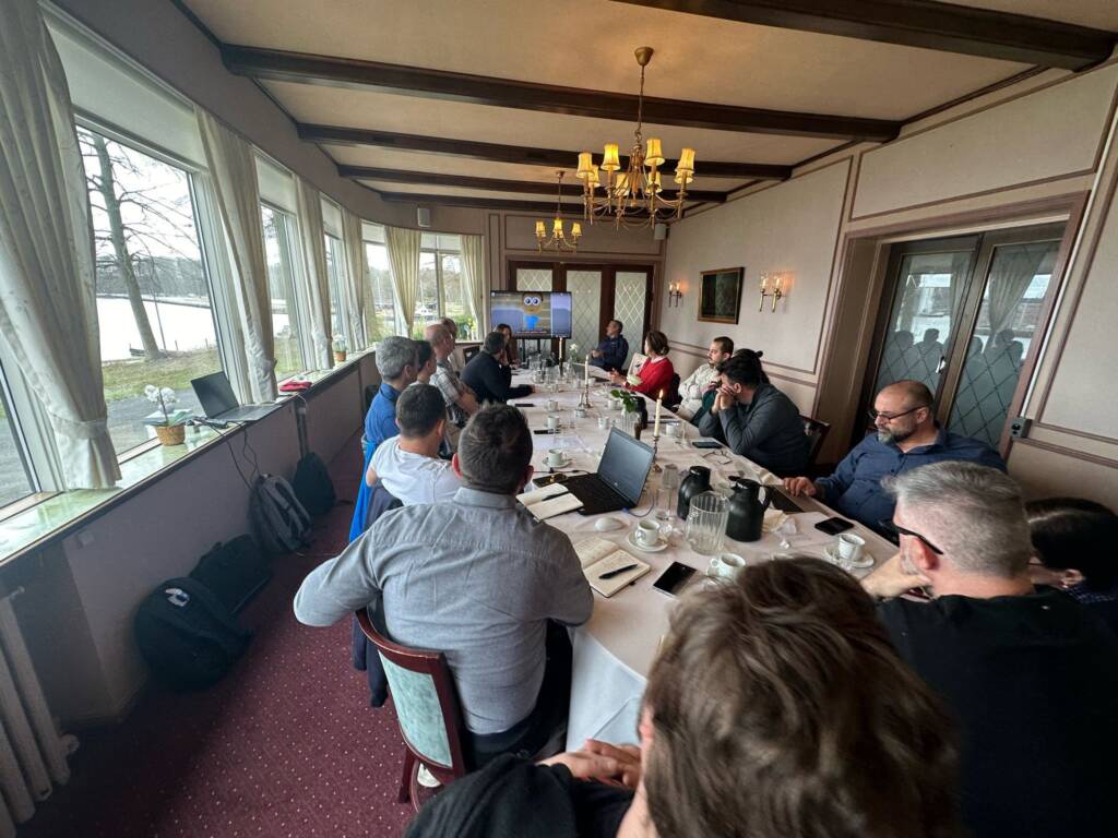 Team gathered around a long table for a presentation in a meeting room.
